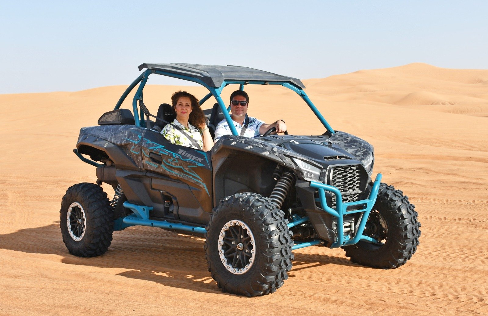 Dubai private Can-Am dune buggy tour features including fully insured ride, private car pickup, expert tour guide, safety convoy, flexible timing, 3000cc buggy engine, sandboarding, safety gear, training, and sunset photo stops