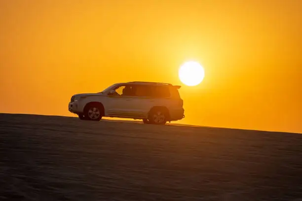 Toyota Land Cruiser on Qatar desert sand dunes at sunset during dune bashing safari