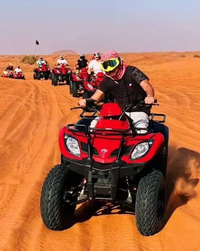 Off-road rider navigating desert dunes on a single-seat ATV during a guided tour in Dubai
