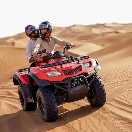 Couple riding a red quad bike together across sand dunes during a Dubai desert safari