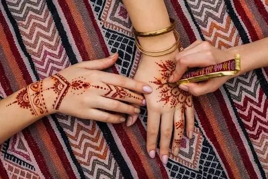 Guest getting traditional henna painting applied to her hand at a Dubai desert safari camp