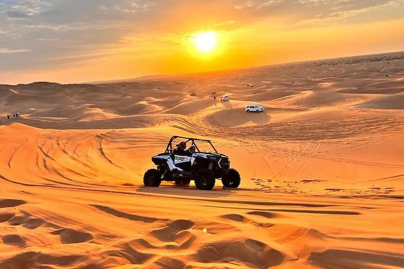 Tourists riding quad bikes on golden sand dunes during a morning desert safari in Dubai