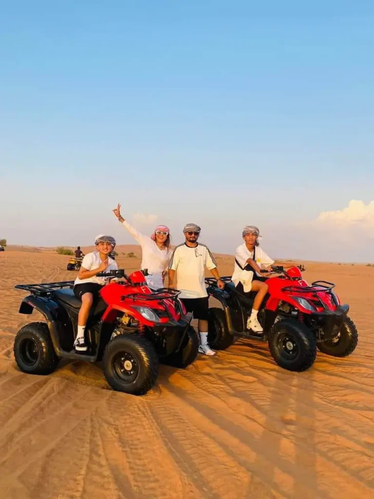 Tourist riding a quad bike across sand dunes during a Dubai morning safari