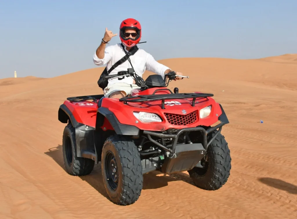Riders on quad bikes crossing desert dunes during a guided quad bike safari in Dubai
