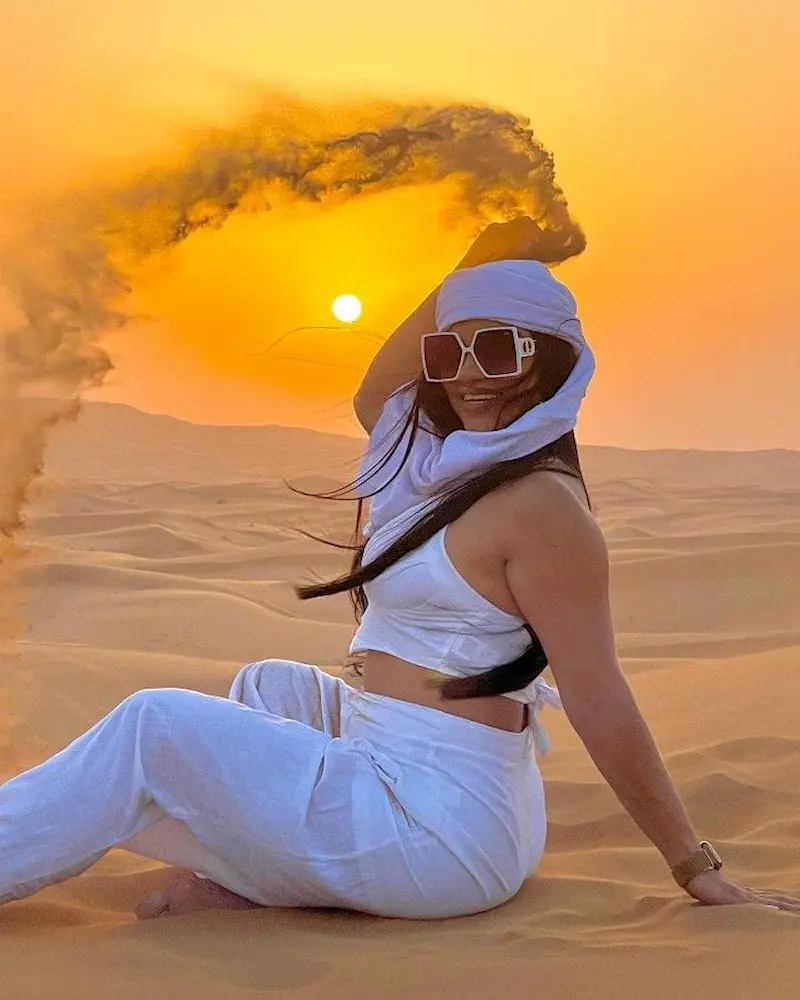 Silhouette of a traveler against a colorful sunrise sky at Dubai desert dunes