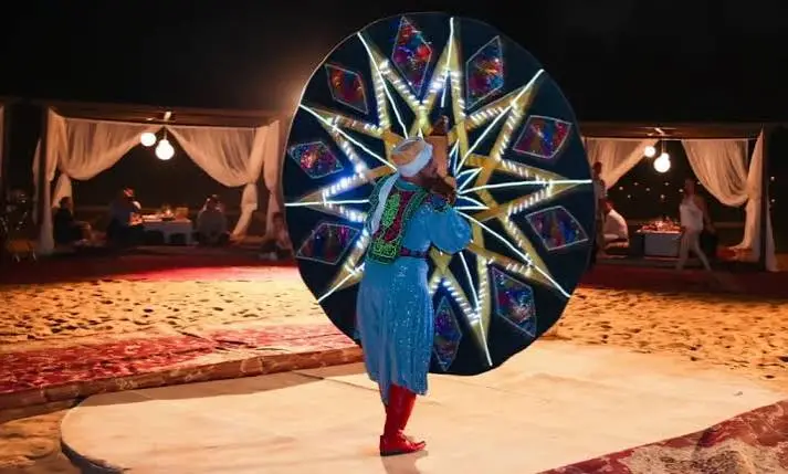 Tanoura dancer spinning in a colorful skirt during a live show at a Dubai desert safari camp